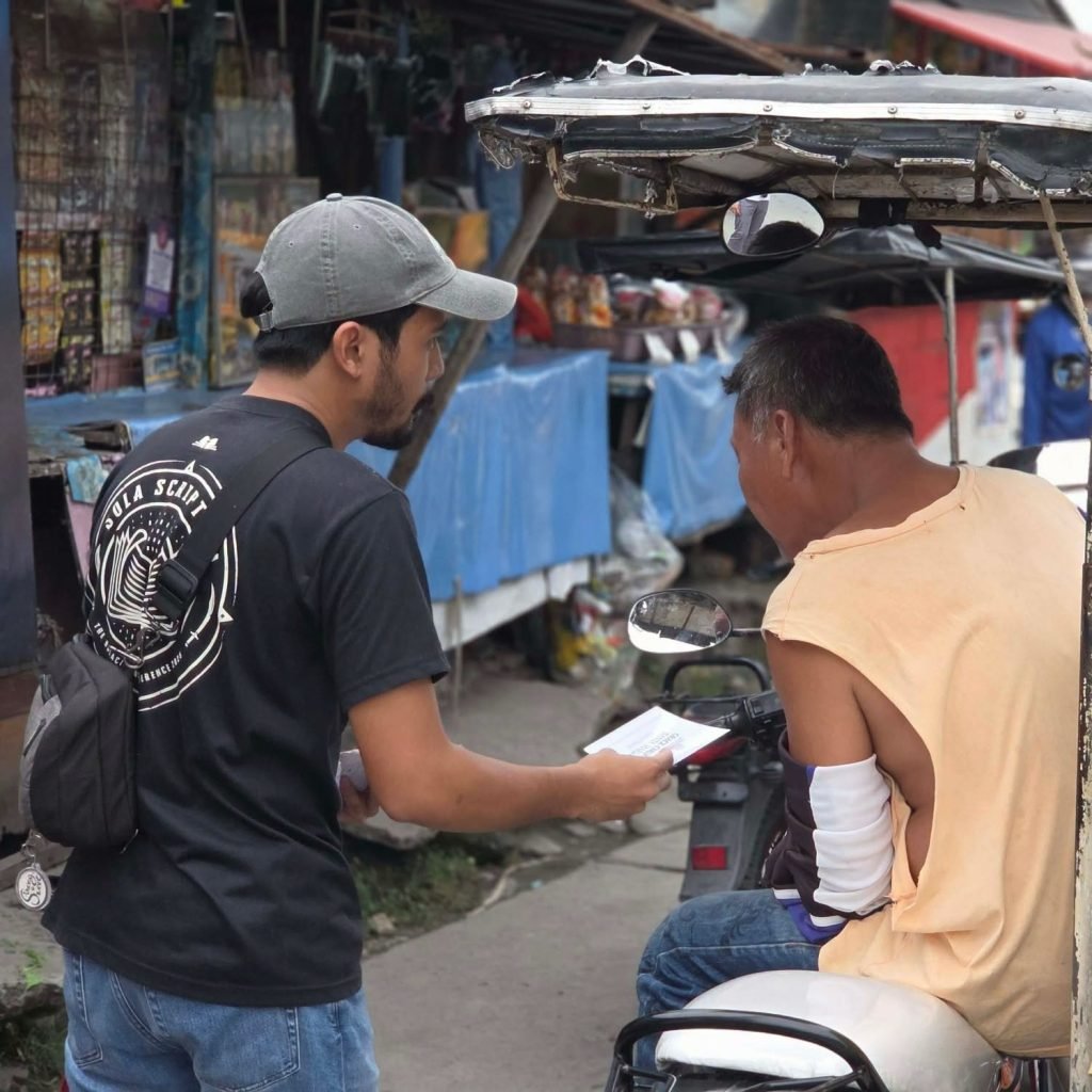 A church member handing a gospel tract to a tricycle driver at the market in Santa Maria